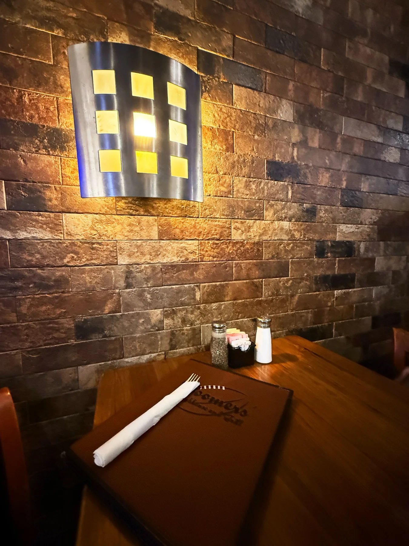 Warm wall lighting over a set wood table at Boomers’